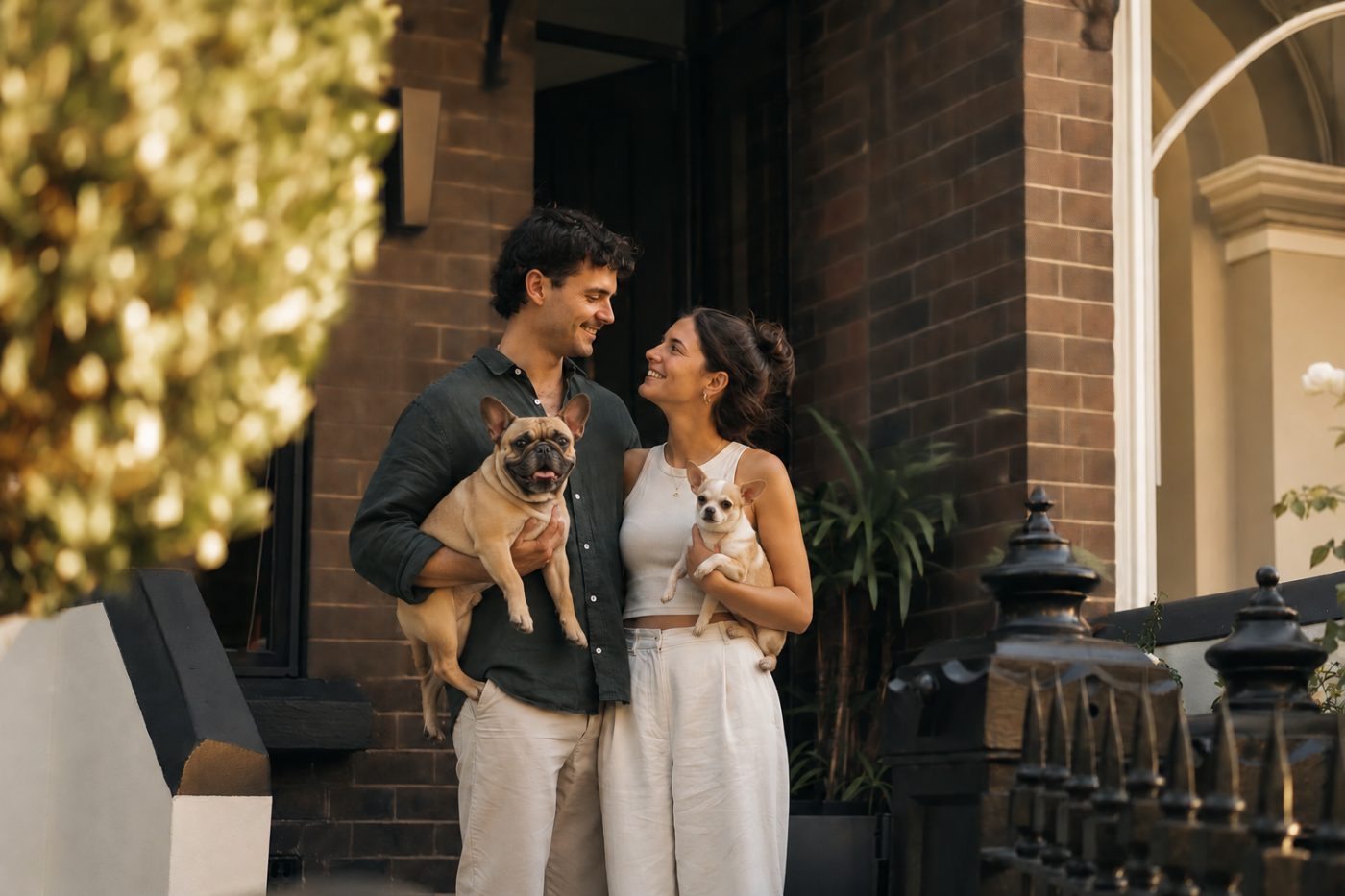 A young couple on the front steps of a Melbourne inner-suburban terrace home in warm afternoon light.